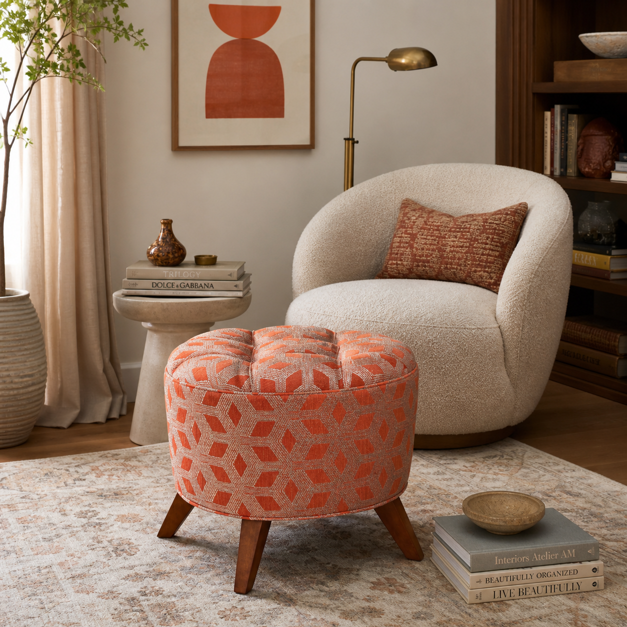 The Valencia orange geometric round ottoman styled in a cozy modern reading nook with boucle chair and warm wood accents