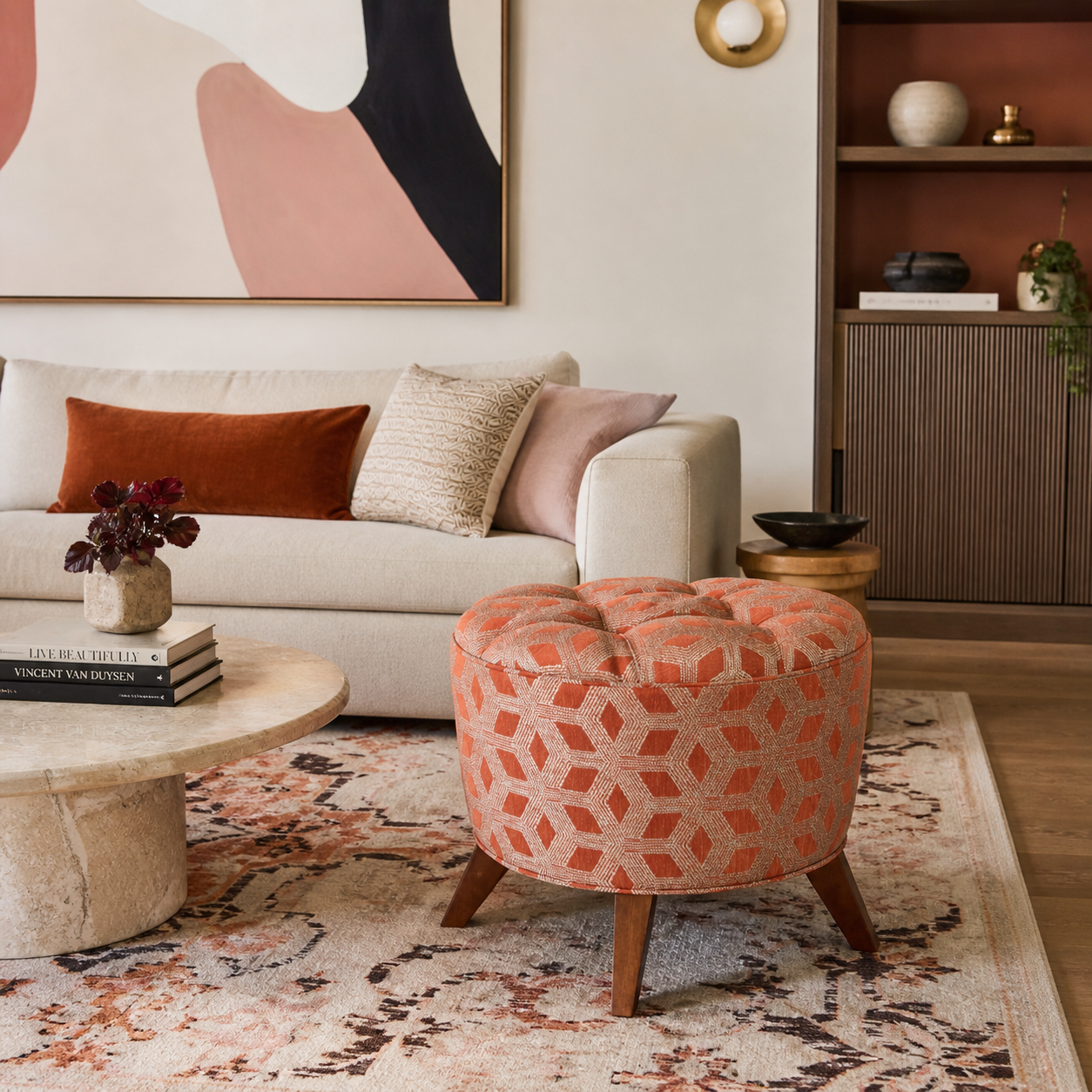 The Valencia tufted orange ottoman in a cozy modern living room with cream sofa warm wood and abstract wall art