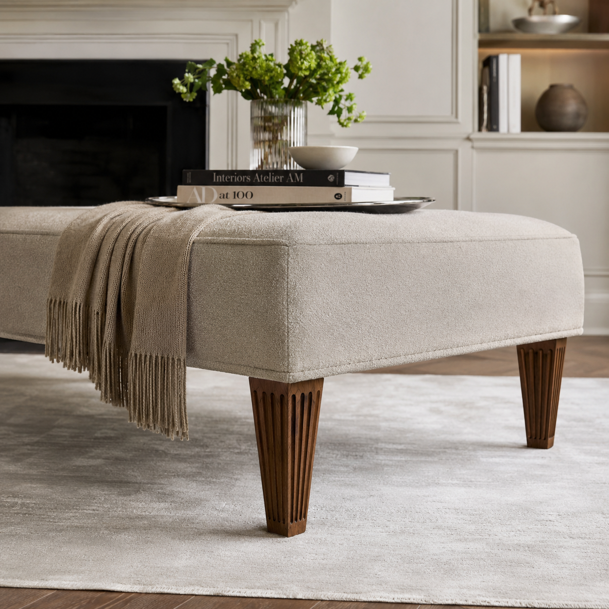 Finished fluted sofa legs in medium wood stain installed on an upholstered ottoman bench in a living room lifestyle scene